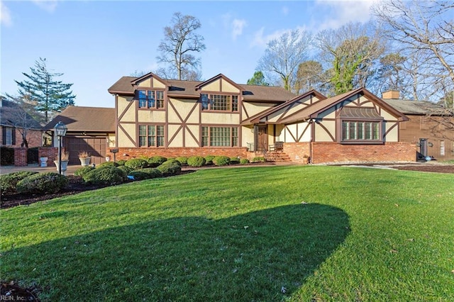 tudor-style house featuring stucco siding, brick siding, and a front yard