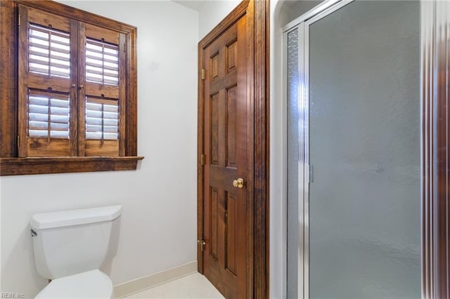 bathroom with baseboards, toilet, and a shower stall
