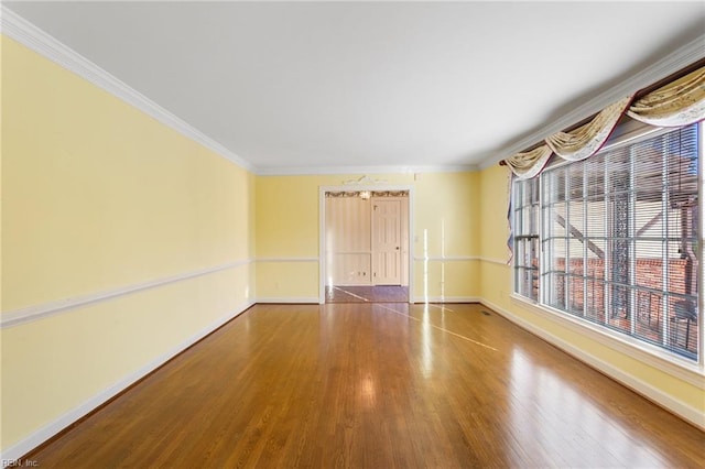empty room featuring baseboards, wood finished floors, and ornamental molding