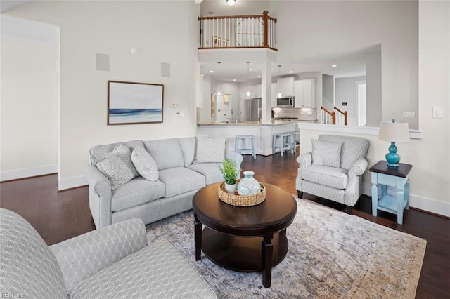 living area featuring recessed lighting, a high ceiling, baseboards, and dark wood-style flooring