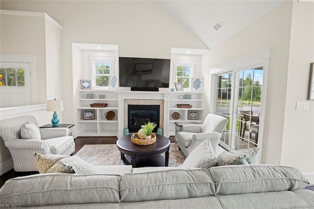 living area featuring visible vents, high vaulted ceiling, a glass covered fireplace, and wood finished floors