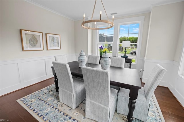 dining space featuring wood finished floors, visible vents, ornamental molding, wainscoting, and a notable chandelier