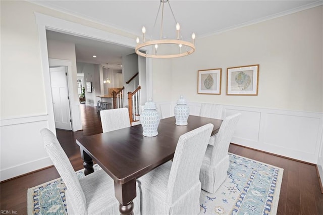 dining space with a notable chandelier, ornamental molding, wood finished floors, stairway, and a decorative wall