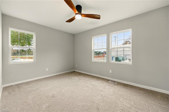 carpeted empty room with visible vents, baseboards, and a ceiling fan