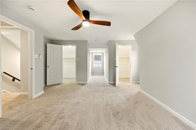 unfurnished bedroom with a spacious closet, baseboards, and light carpet