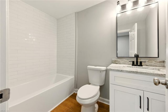 bathroom featuring toilet, shower / washtub combination, wood finished floors, baseboards, and vanity