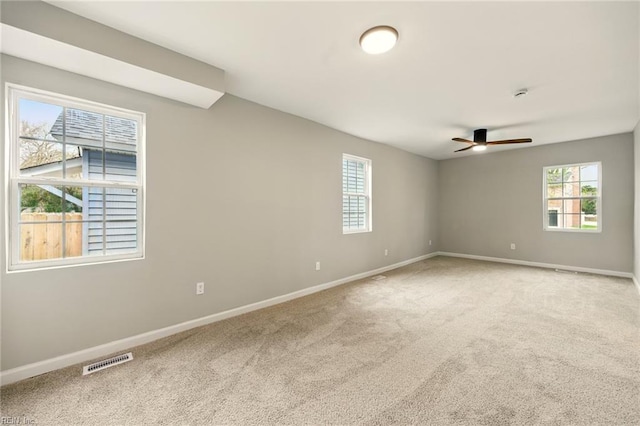 carpeted spare room featuring visible vents, baseboards, and ceiling fan