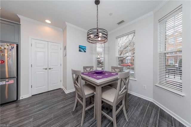 dining area featuring an inviting chandelier, ornamental molding, and wood tiled floor