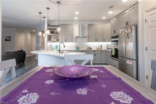 kitchen featuring open shelves, a sink, gray cabinetry, appliances with stainless steel finishes, and wall chimney exhaust hood