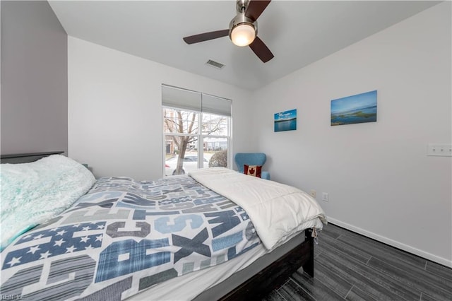 bedroom featuring ceiling fan, visible vents, baseboards, and wood finished floors