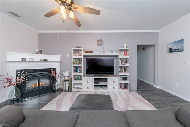 living room with a glass covered fireplace, crown molding, dark wood-style floors, and visible vents