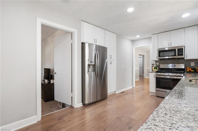 kitchen featuring backsplash, recessed lighting, stainless steel appliances, white cabinets, and light wood finished floors