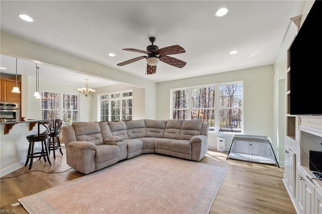 living area with baseboards, ceiling fan with notable chandelier, light wood-style floors, and recessed lighting