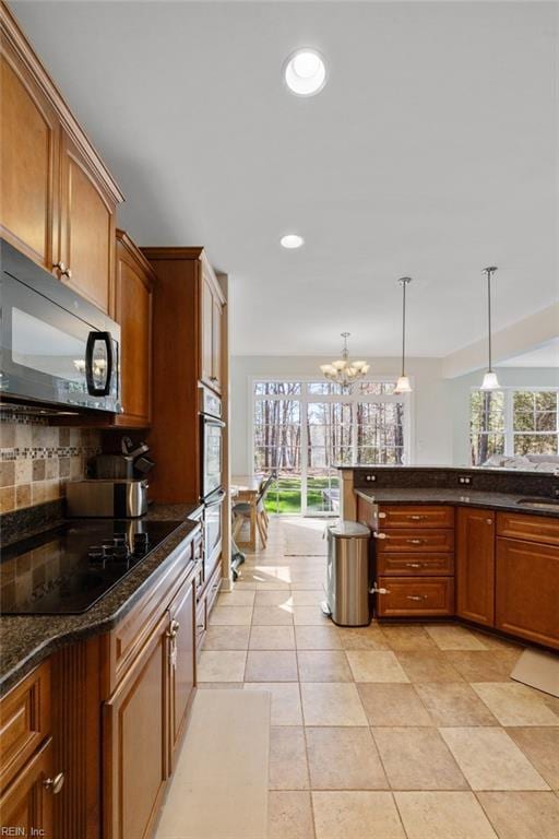 kitchen featuring backsplash, pendant lighting, black appliances, recessed lighting, and an inviting chandelier