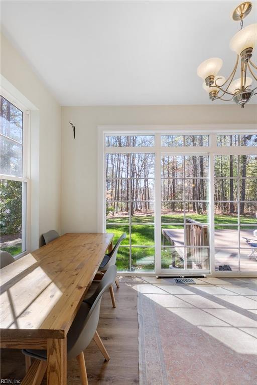 dining room featuring a healthy amount of sunlight, wood finished floors, and an inviting chandelier