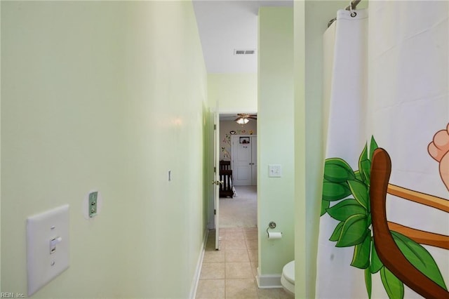 hallway featuring light tile patterned flooring, baseboards, and visible vents