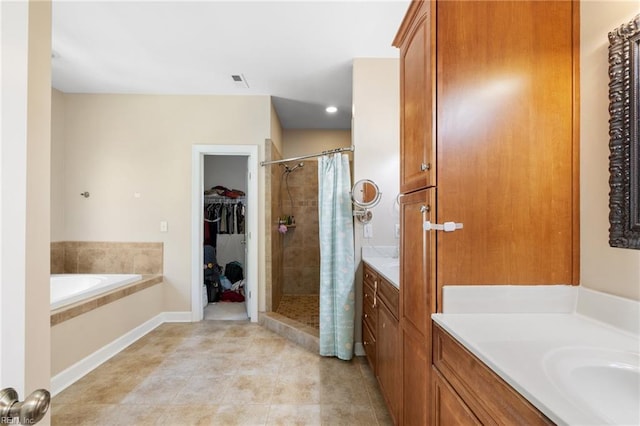 bathroom with a stall shower, tile patterned floors, vanity, a garden tub, and a spacious closet