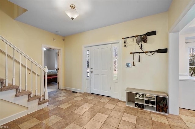 entrance foyer with baseboards, washer / clothes dryer, and stairway