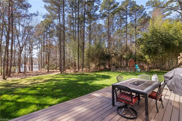 wooden deck with a playground, outdoor dining space, and a yard