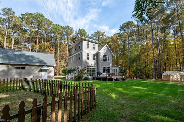 back of house featuring a lawn, a wooden deck, an outbuilding, and fence