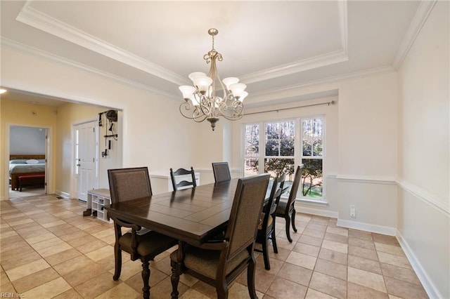 dining space with crown molding, baseboards, an inviting chandelier, and a raised ceiling