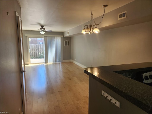 unfurnished dining area featuring light wood-style flooring, baseboards, a chandelier, and a ceiling fan