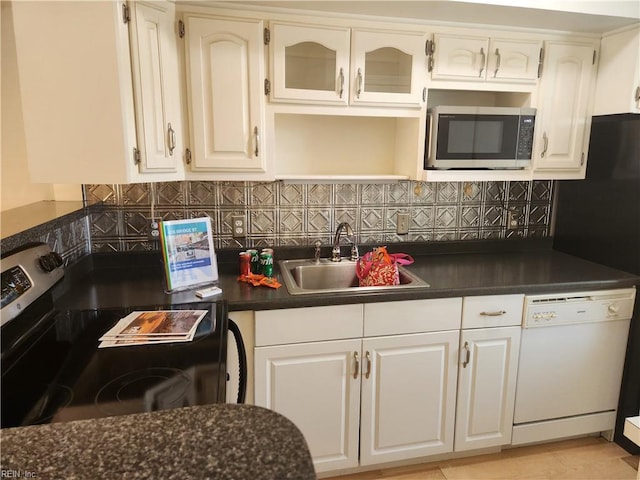 kitchen with appliances with stainless steel finishes, a sink, dark countertops, and backsplash