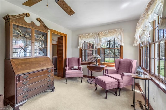 sitting room with baseboards, a ceiling fan, and light colored carpet