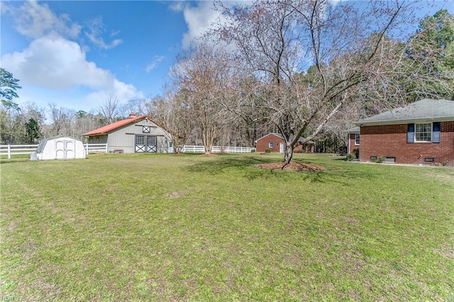view of yard featuring a storage unit, an outbuilding, a barn, and fence