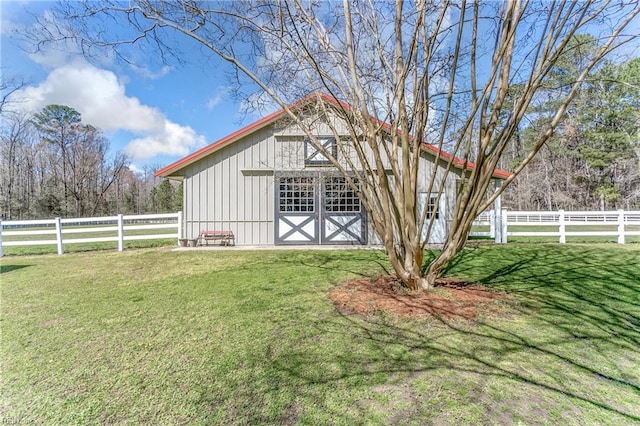 view of barn with fence and a lawn