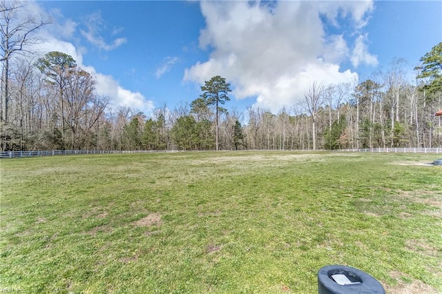 view of yard featuring a forest view and fence