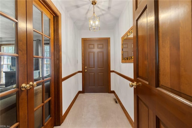 entryway with visible vents, a chandelier, baseboards, light carpet, and french doors