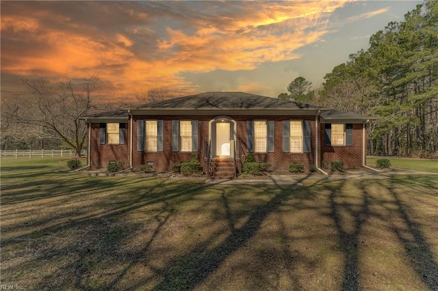 ranch-style home featuring brick siding, fence, and a yard