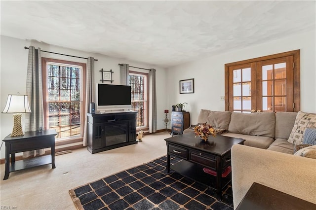 carpeted living area with a wealth of natural light, a fireplace, french doors, and baseboards