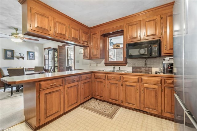 kitchen featuring brown cabinetry, black microwave, and light floors