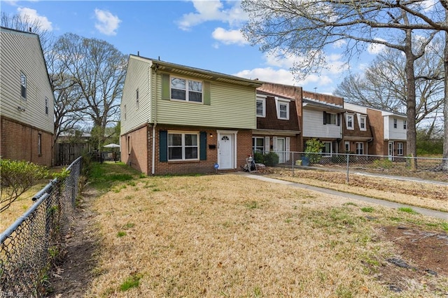 view of front of property with a front yard, a fenced backyard, and brick siding