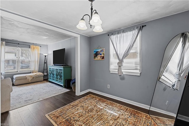 interior space with a chandelier, baseboards, and wood finished floors