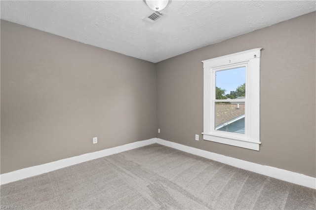 carpeted empty room with visible vents, a textured ceiling, and baseboards