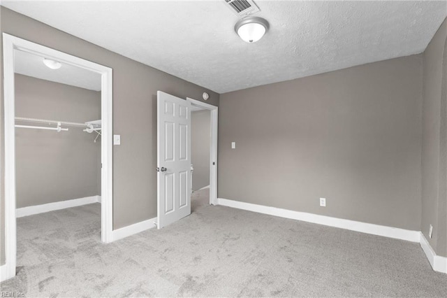 unfurnished bedroom featuring carpet, visible vents, a closet, and a textured ceiling
