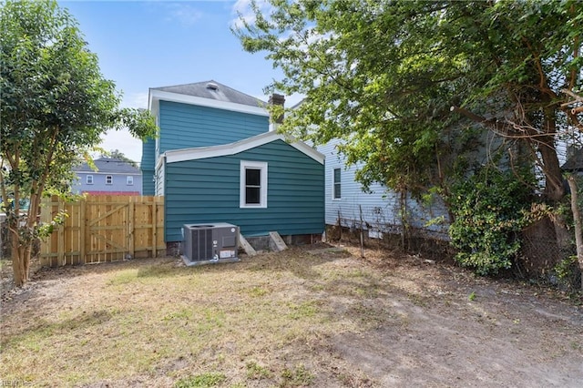 rear view of house with a yard, central AC unit, and fence
