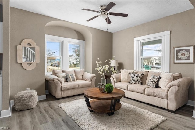 living area featuring wood finished floors, a ceiling fan, and a textured wall