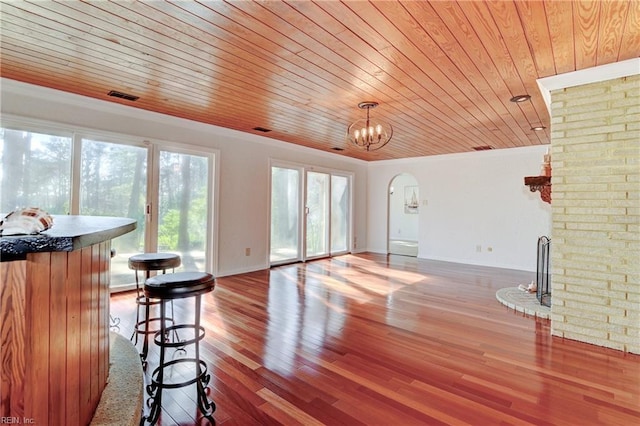 living room with wood finished floors, visible vents, arched walkways, wood ceiling, and crown molding