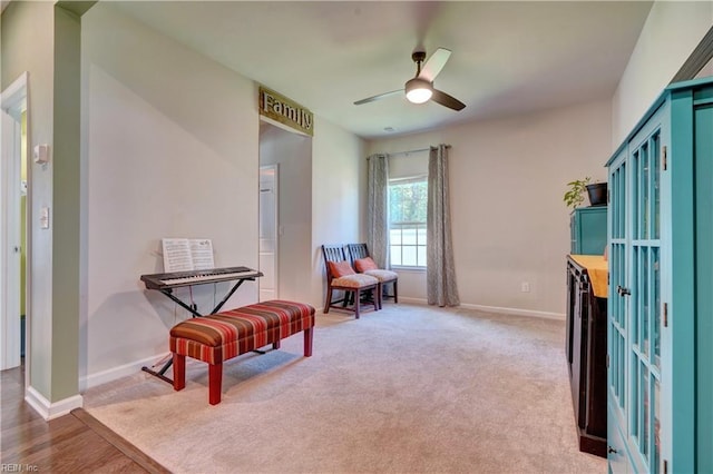 living area with light colored carpet, baseboards, and ceiling fan