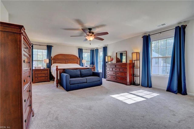 bedroom with light carpet, visible vents, and a ceiling fan