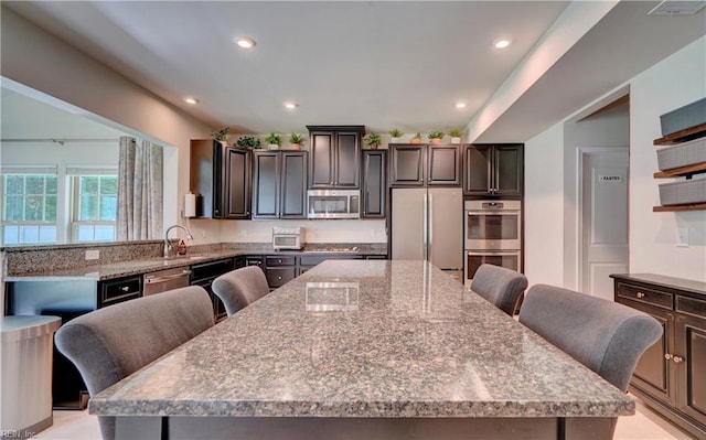 kitchen featuring a breakfast bar area, a spacious island, recessed lighting, a sink, and appliances with stainless steel finishes