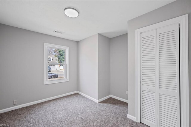 unfurnished bedroom featuring carpet flooring, baseboards, visible vents, and a closet