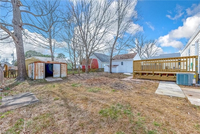 view of yard featuring an outbuilding, a shed, central air condition unit, and a deck