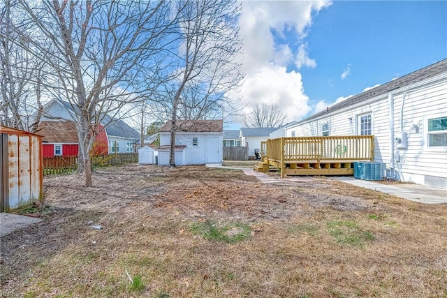 view of yard featuring an outbuilding, central AC, fence, a shed, and a wooden deck