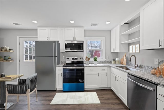 kitchen with open shelves, stainless steel appliances, visible vents, and a sink