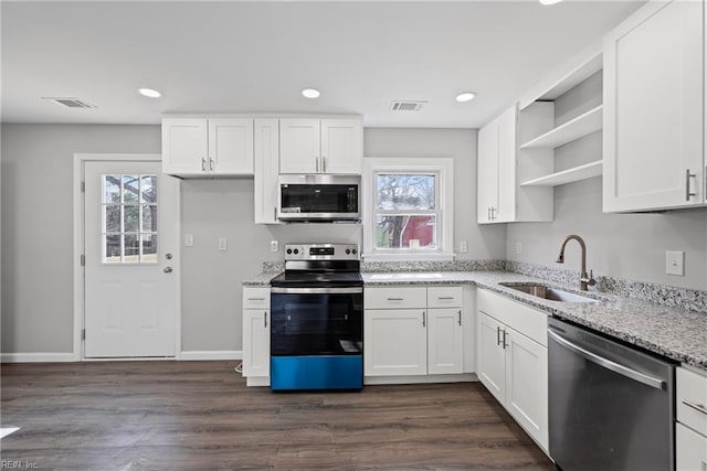kitchen with visible vents, a sink, light stone counters, stainless steel appliances, and open shelves